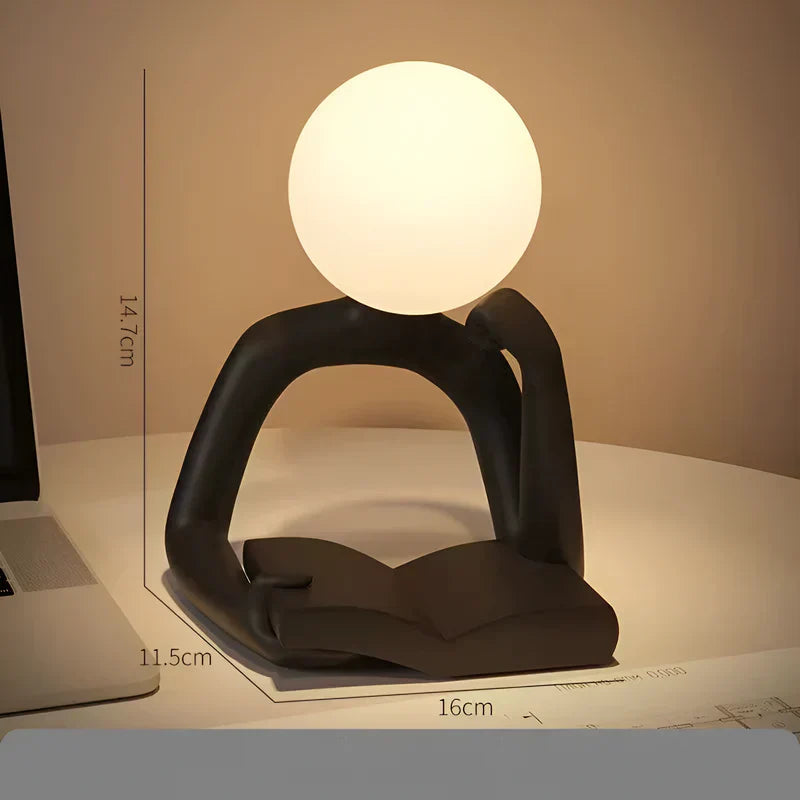Konstnärlig bordslampa i form av en läsande figur i plast